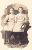 Real photo postcard front. 2 Girls Sitting in A Chair